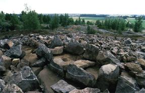 Kokemäen Orjapaaden röykkiön paasiarkku. Sisämaassa sijaitsevasta röykkiöstä löytyi useita polttohautauksia. Röykkiön reunaosien kolmesta hautauksesta nuorin on nuoremmalta roomalaiselta rautakaudelta 200-400 jKr. Yksi palaneen luun keskittymä näkyy kuvassa paasiarkun keskiosassa. Kuva: TYA 47:38  T. Tuovinen.
